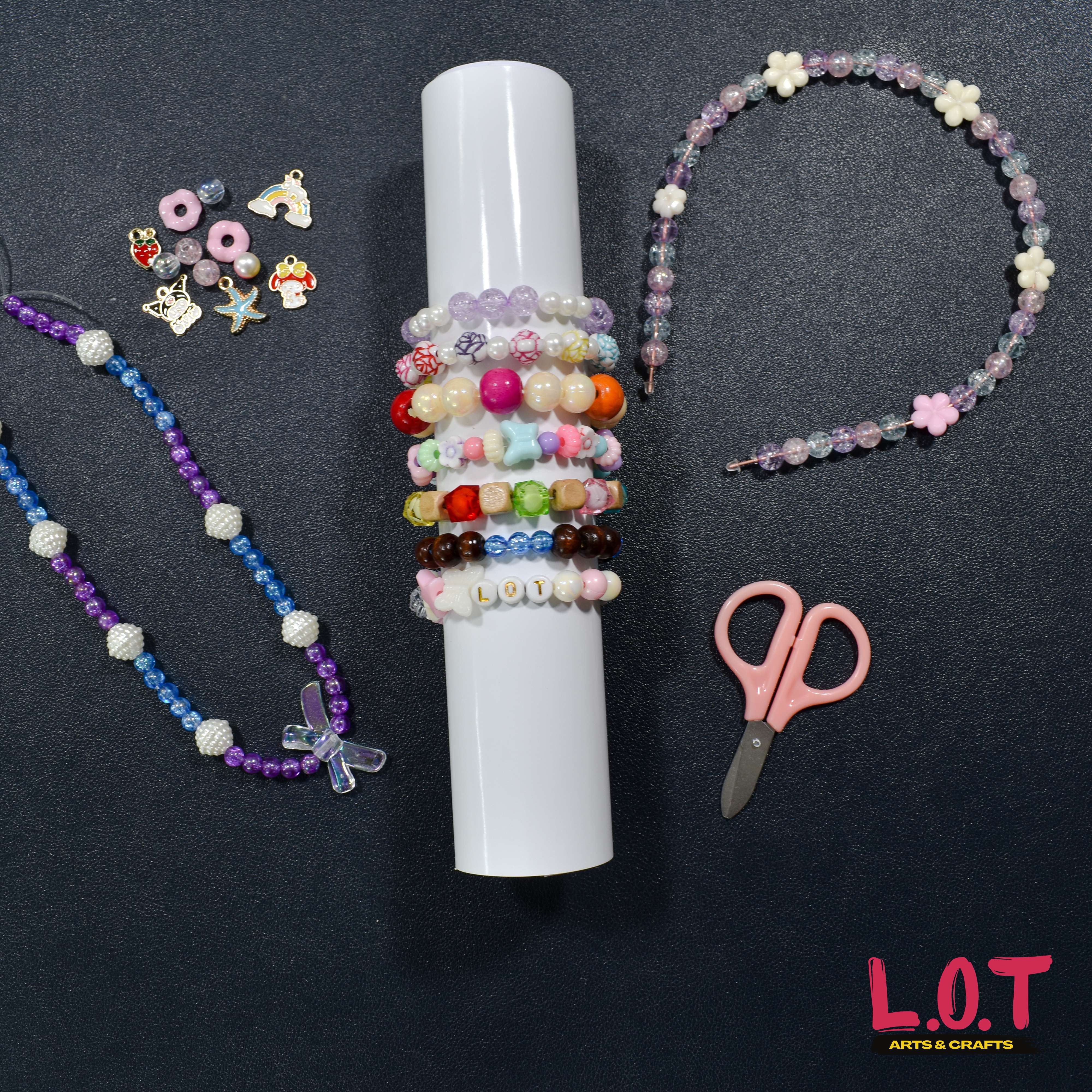 Beaded necklaces, bracelets, and a pair of scissors on a dark surface with 'L.O.T Arts & Crafts' branding.